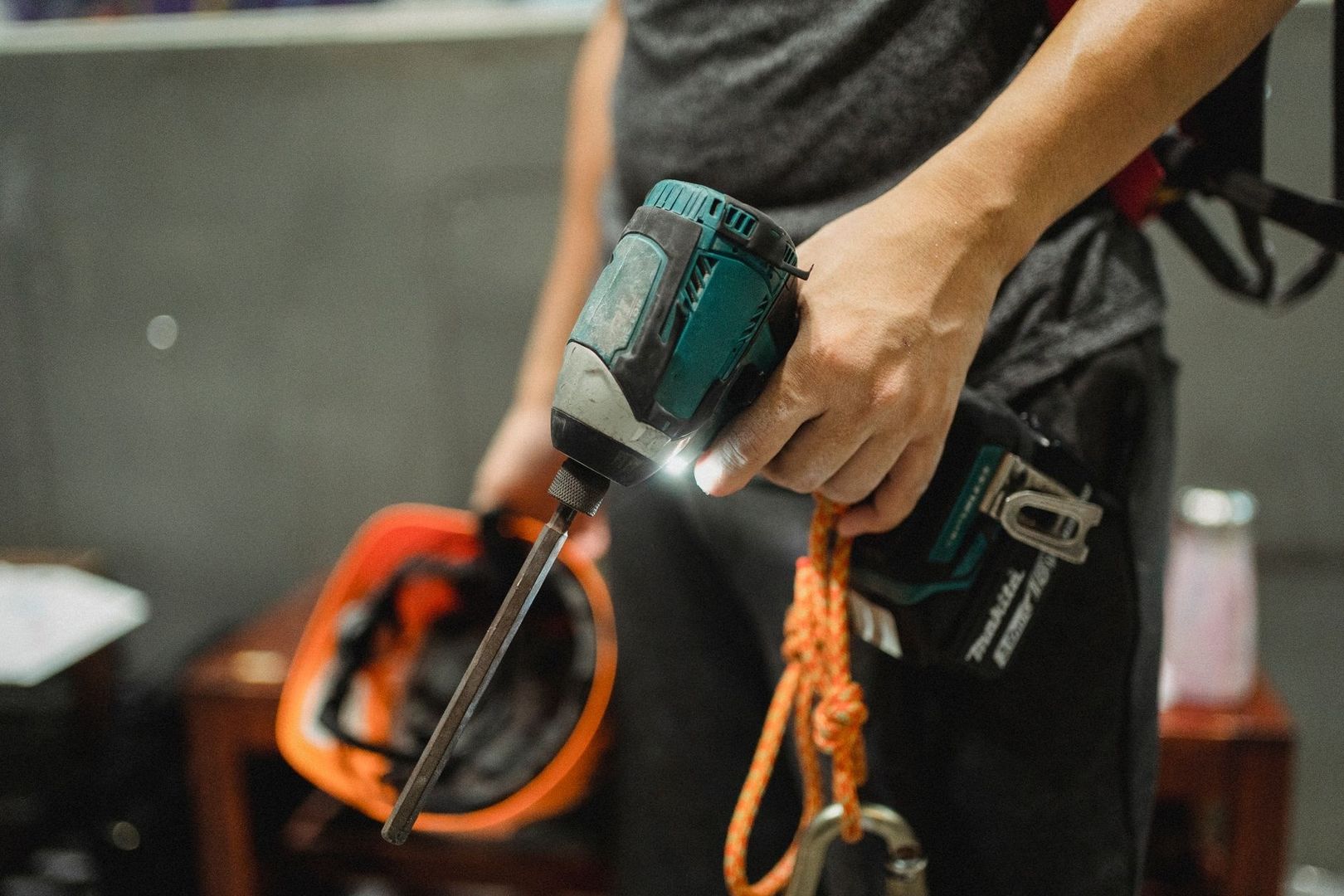 Worker holding a powered hand tool with a long bit and safety gear